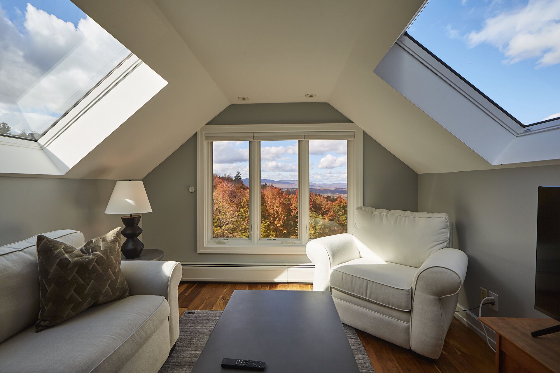 Skylit loft at Whispering Pines Lodge, a Far & Away managed vacation rental near Stratton Mountain, with autumn foliage and the Vermont hills through the window