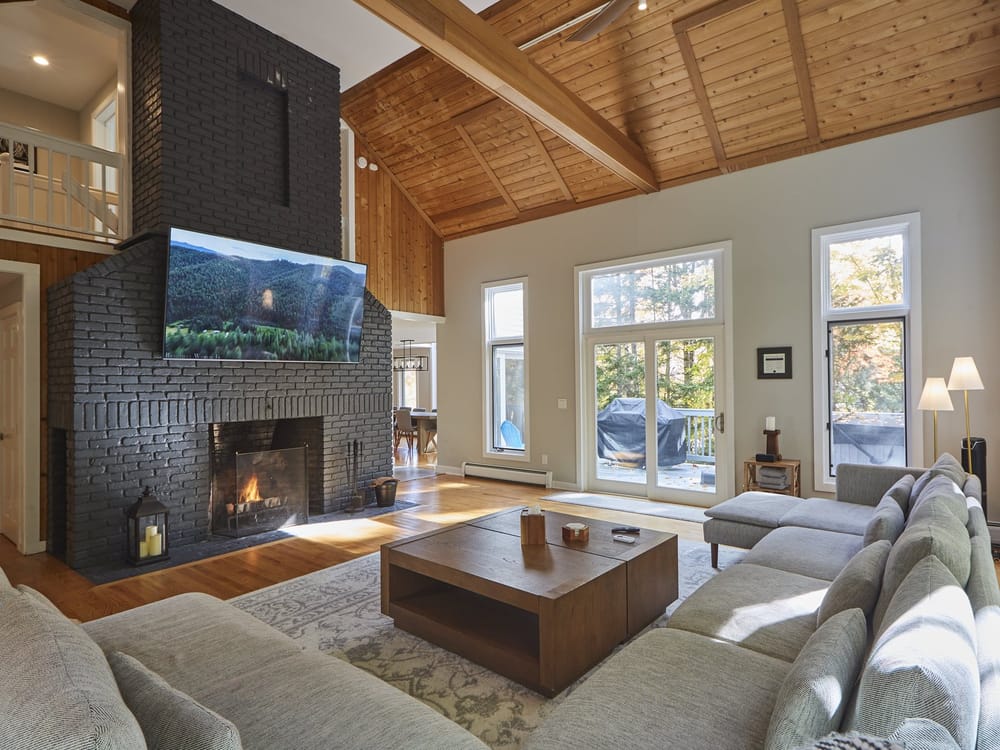 First Chair Lair great room with a black brick fireplace, TV, and vaulted wood ceiling