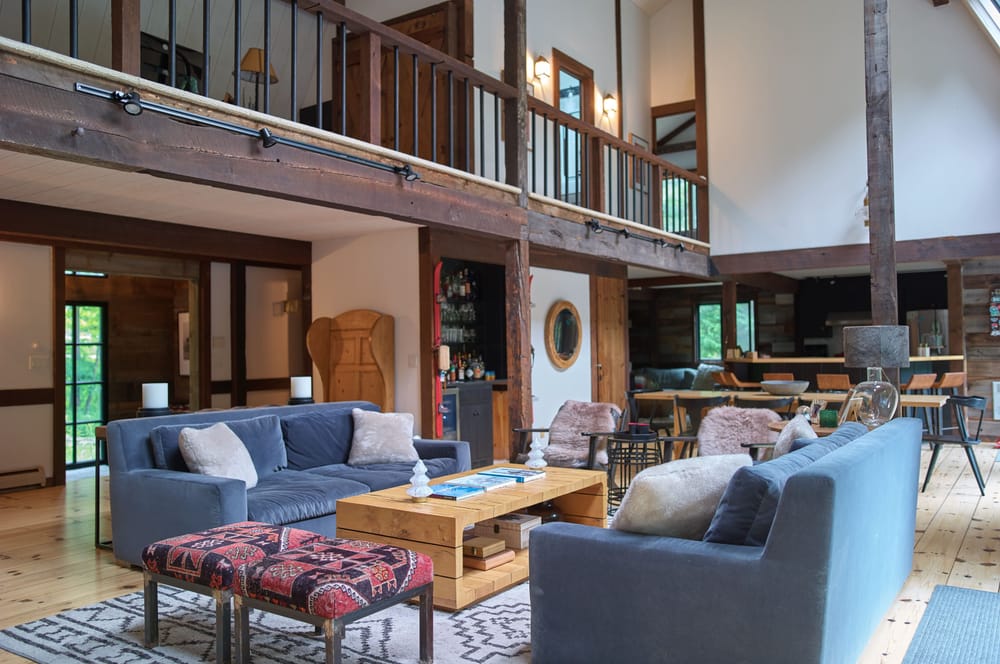 Living and dining area at Apres Lodge in Winhall, Vermont, with a stone fireplace, loft, and wet bar