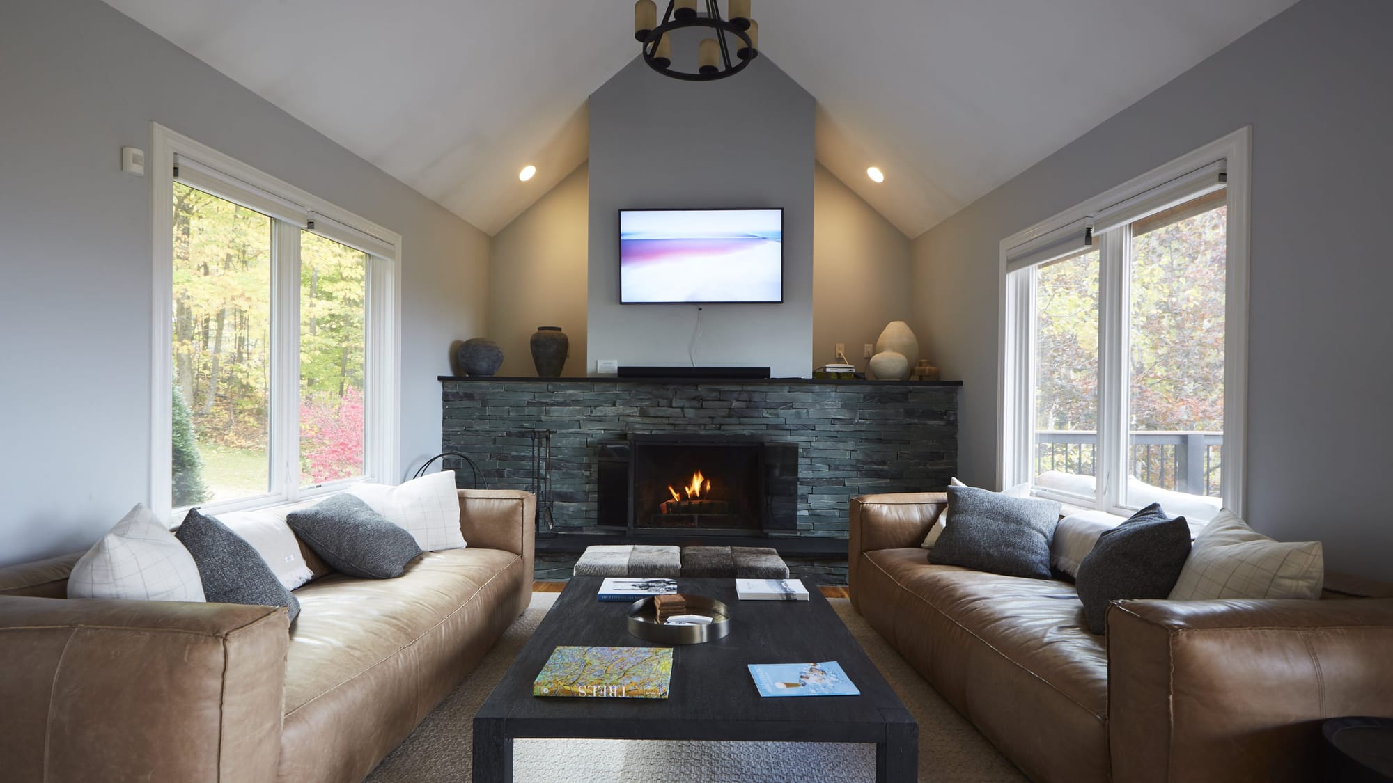 Living room with a lit stone fireplace at a Far & Away managed vacation rental near Stratton Mountain