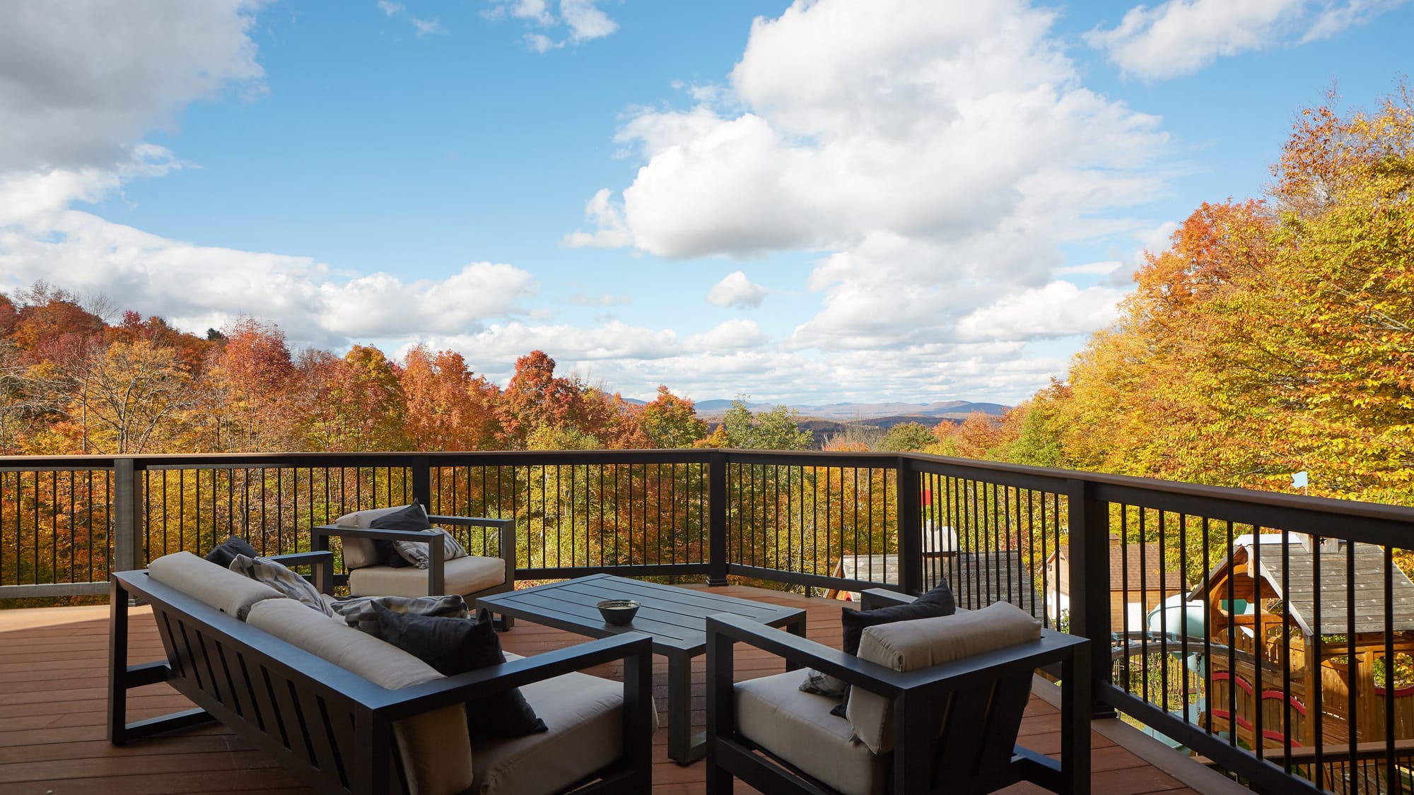 Deck seating at a Far & Away managed home in southern Vermont looking out over autumn foliage and the Green Mountains