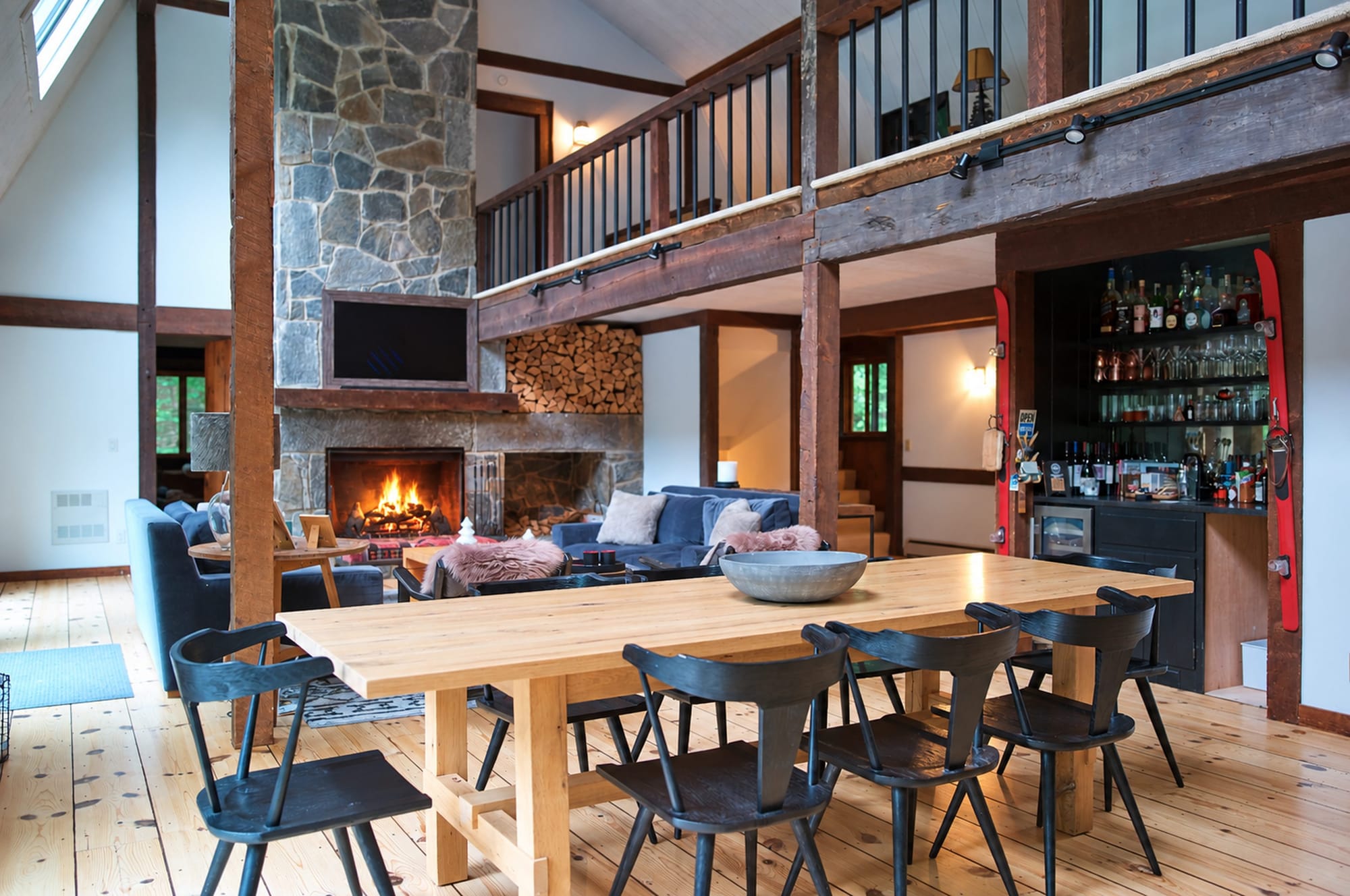 Living and dining area at Apres Lodge in Winhall, Vermont, with the stone fireplace lit